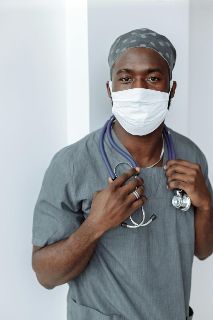 pexels-photo-5327656-5327656 Portrait of a healthcare worker wearing a face mask and scrubs, demonstrating COVID-19 safety measures.