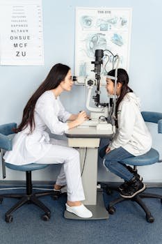 An optometrist performing an eye examination on a young girl in a clinic setting.